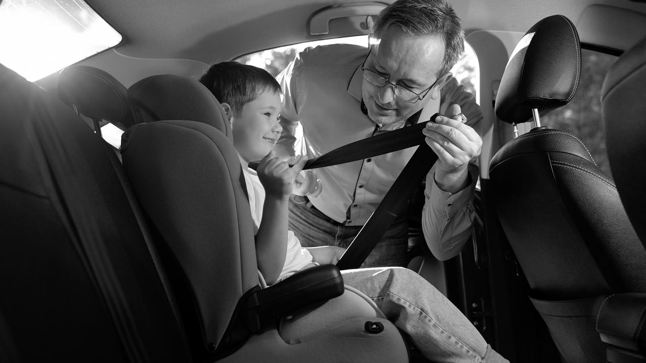 Father secures a child in a car seat