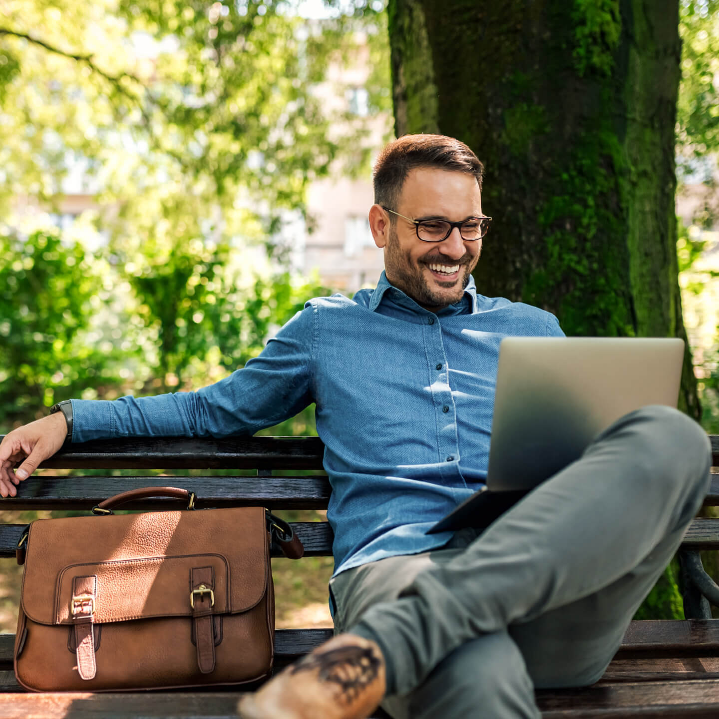Man sitting on park bench working on computer
