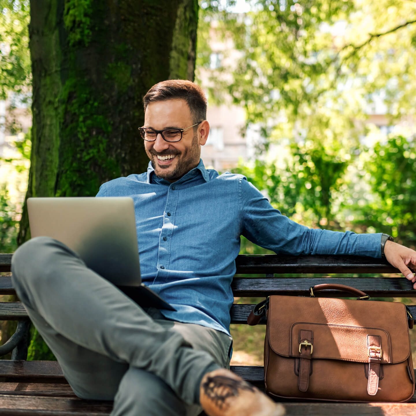 Man sitting on park bench working on computer