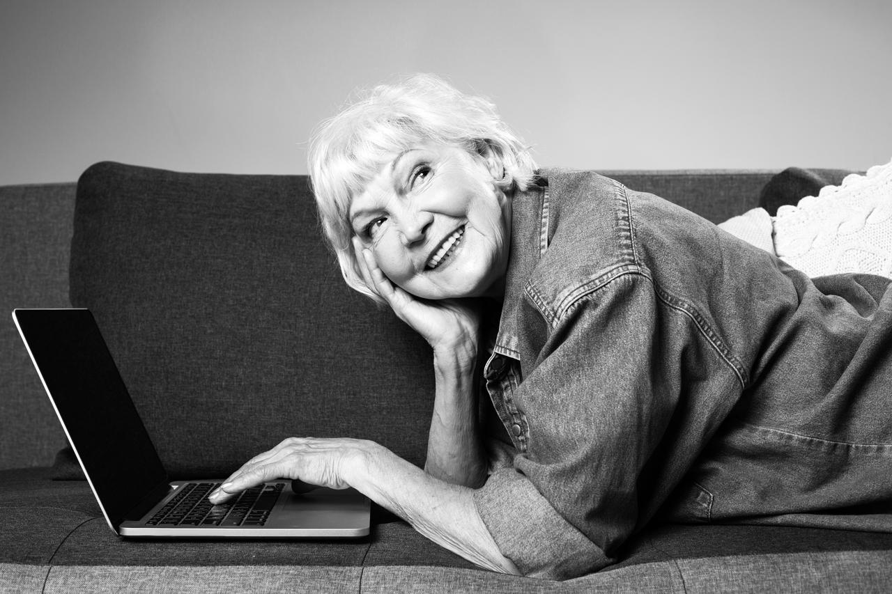 A curious lady resting on the couch with a laptop