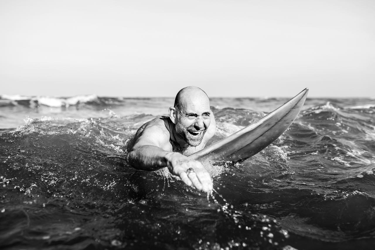 A senior man on a surfboard
