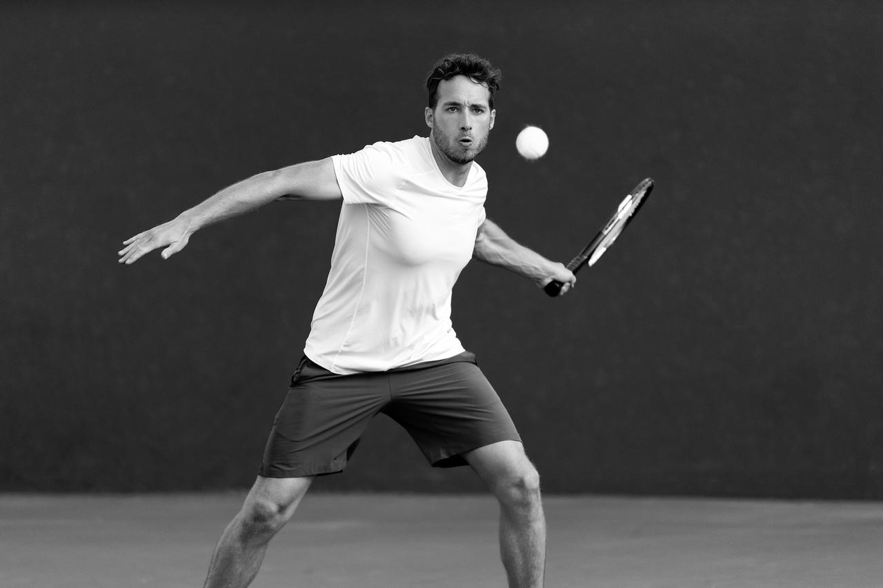 Black and white photo of a man hitting a tennis ball.