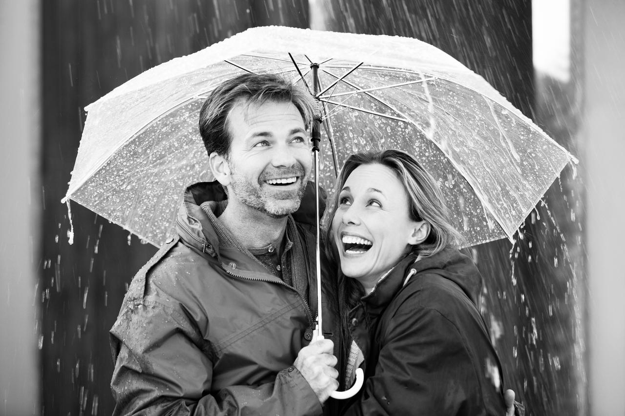 A woman and man huddle under an umbrella in the rain