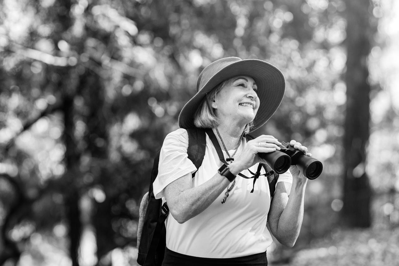 Active senior woman using binoculars to see the beauty of nature