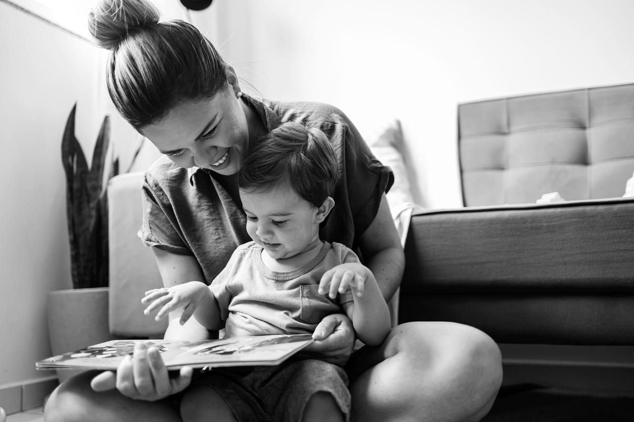 Mother reading a book to her child on the floor