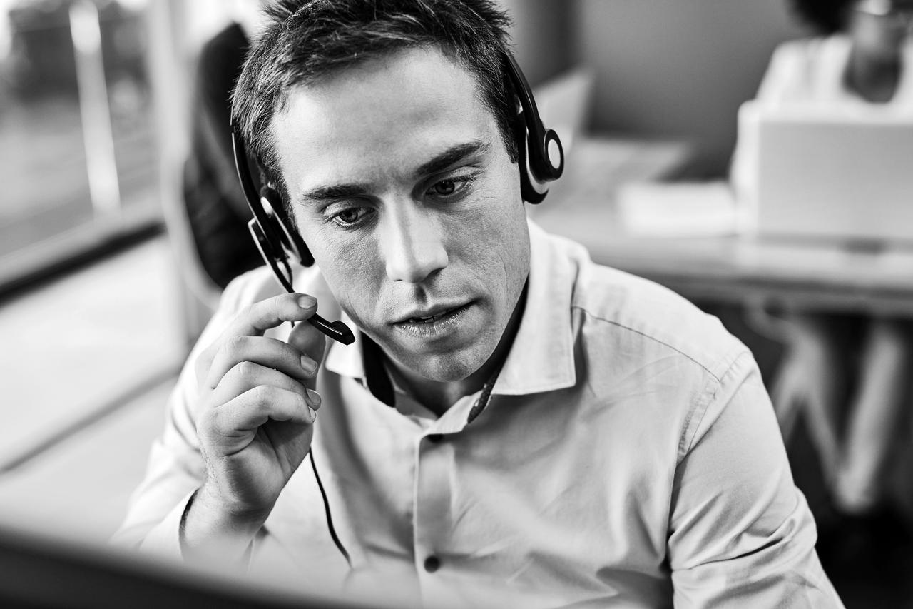A young man in a call centre wearing a headset & providing help