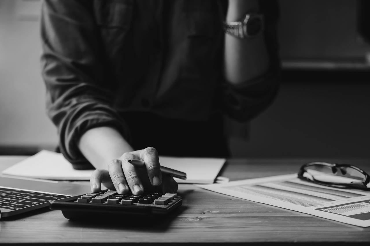 Business woman entrepreneur using a calculator with a pen in her hand, calculating financial expense