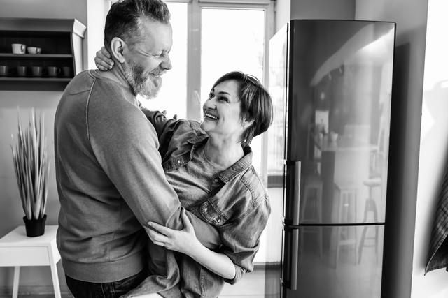 Smiling couple standing up and hugging in the kitchen