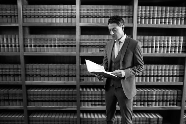 A man in a suit reading a book in a library