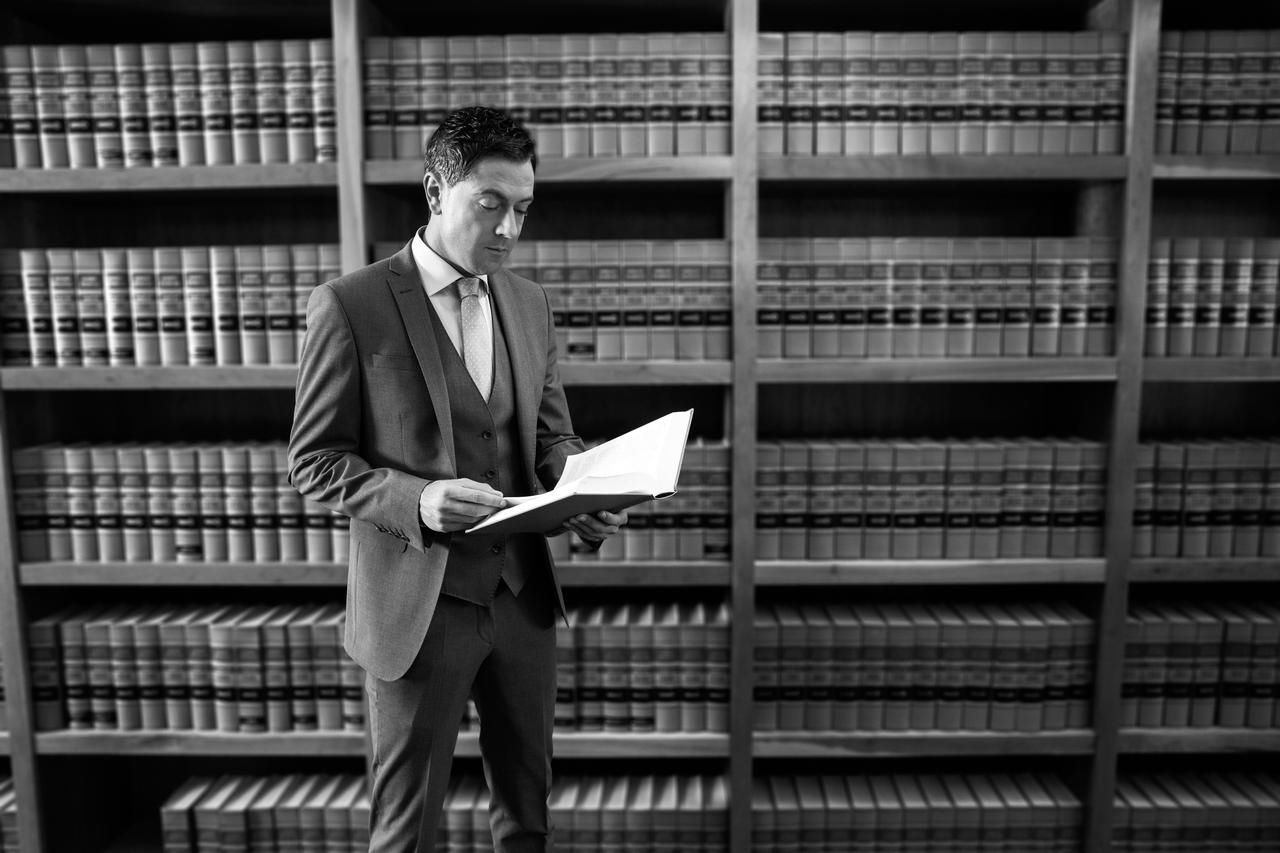 A man in a suit reading a book in a library