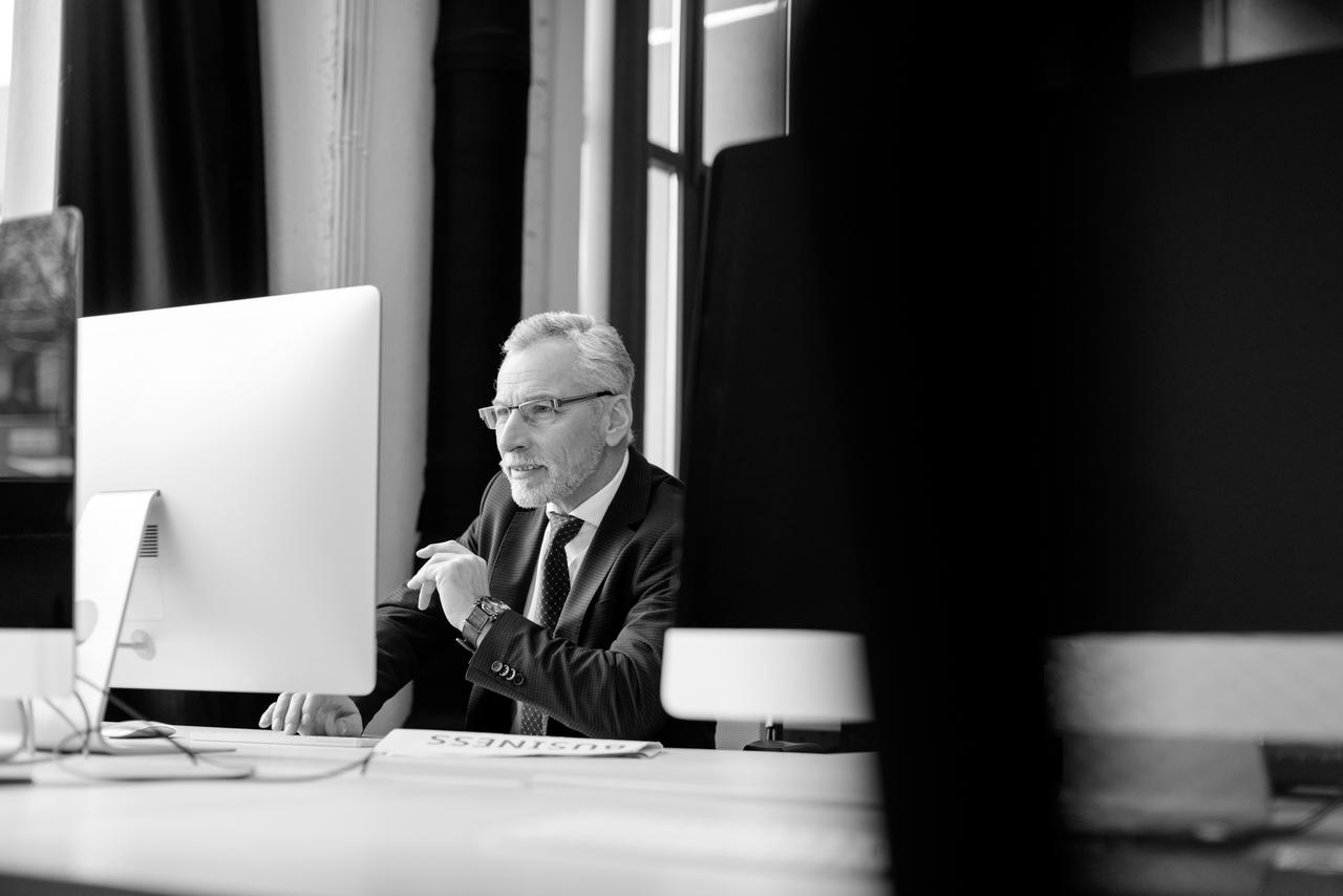 Mature business man sitting at a computer wearing glasses