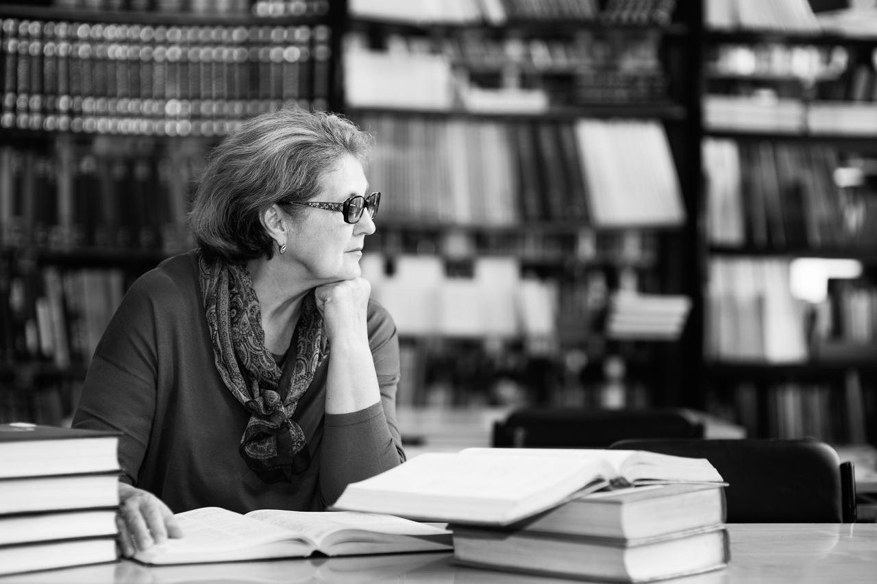 Thoughtful elderly woman in library.