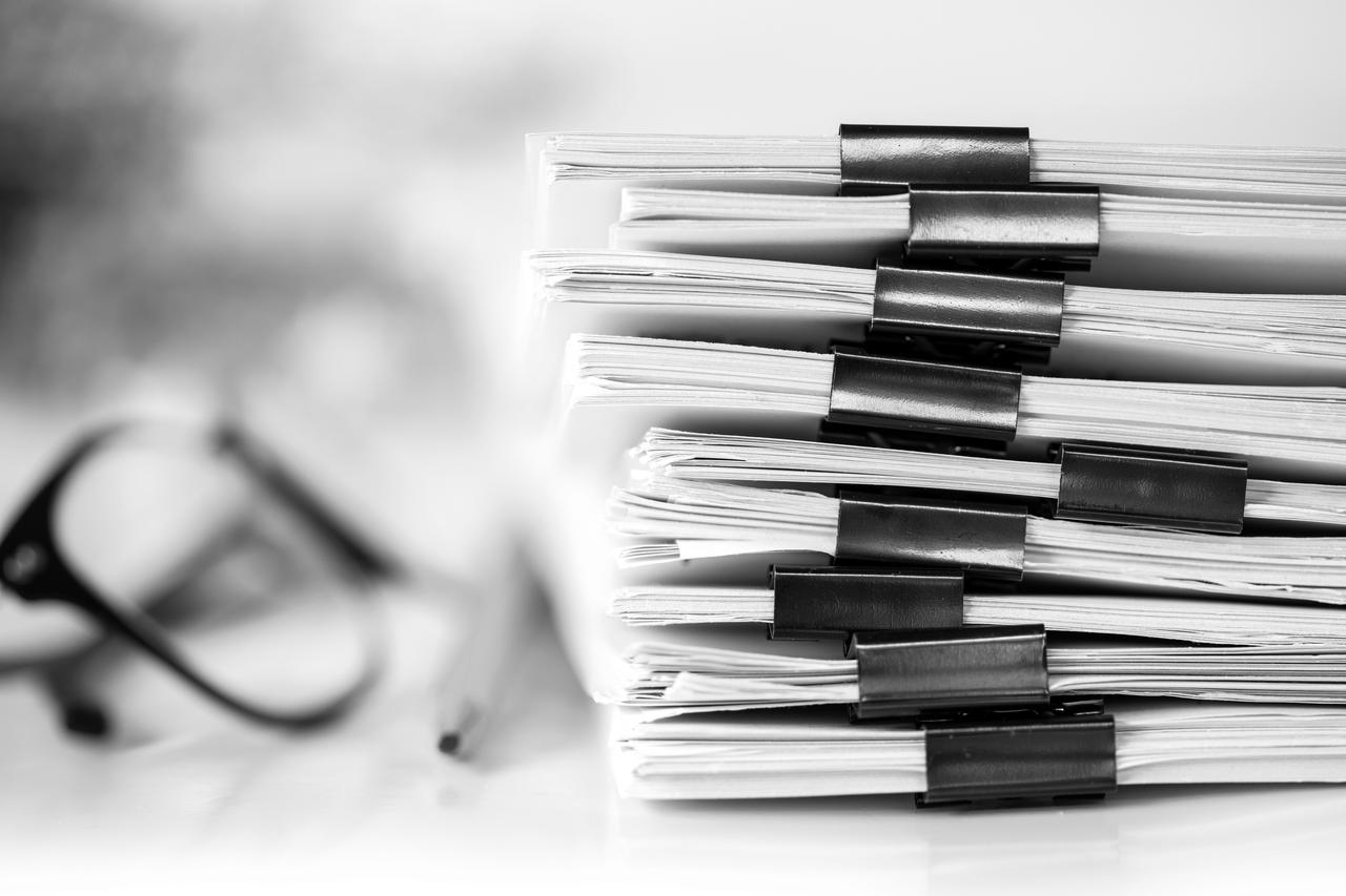 Close up of pair of glasses and stack of document folder
