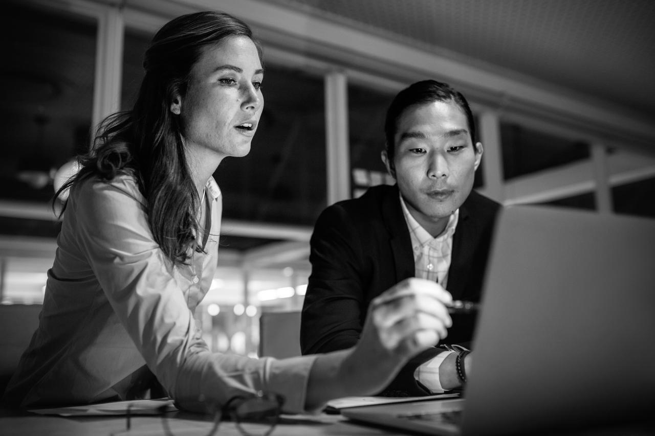 Businesswoman pointing at laptop screen explaining work to business partner