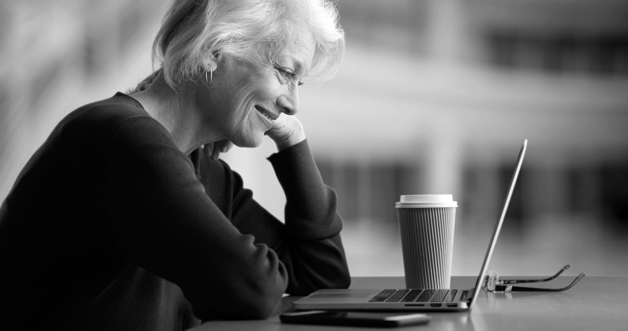 woman in profile with laptop and coffee smiling 1280x675.jpg