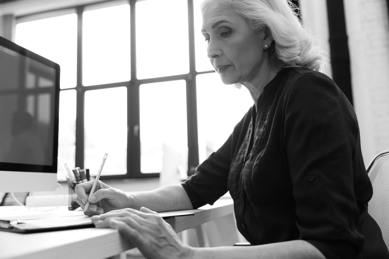 Senior business woman writing down notes on a notepad Senior business woman or lawyer taking notes and looking concentrated